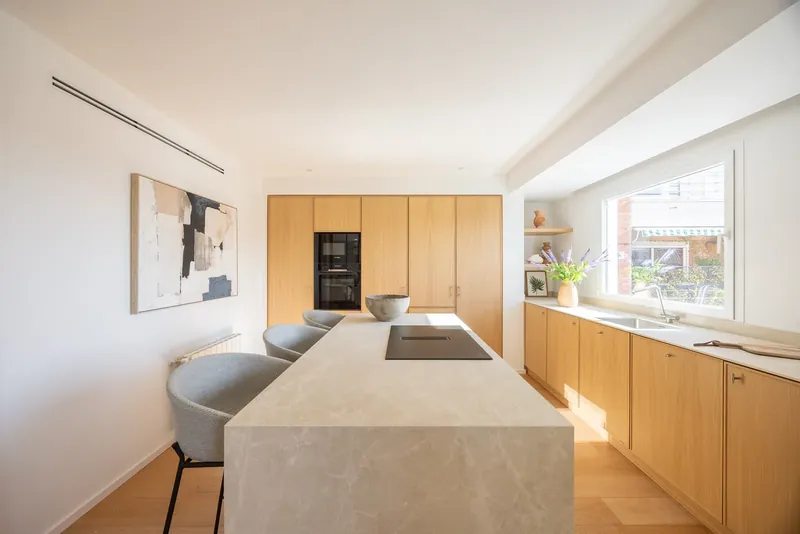 Cocina con frentes de roble y gran isla de piedra