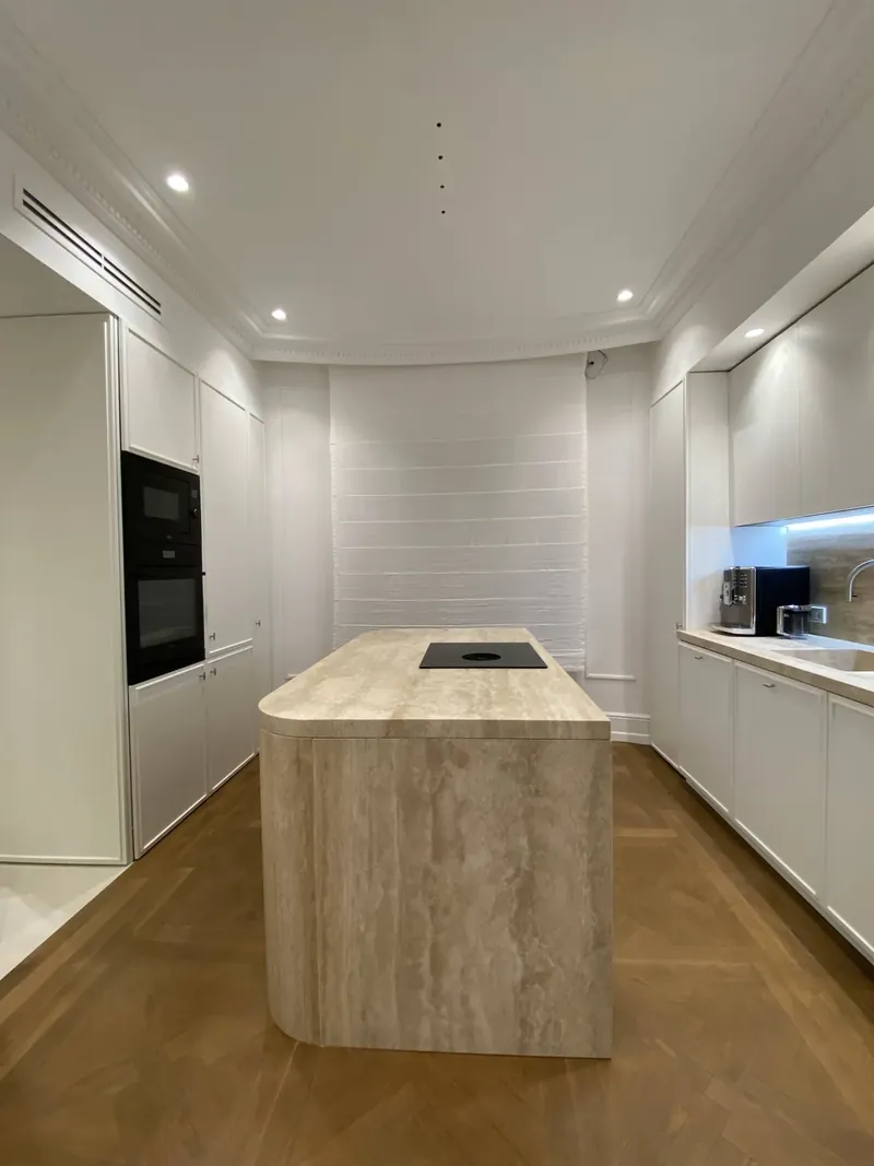 Cocina lacada en blanco con isla de travertino